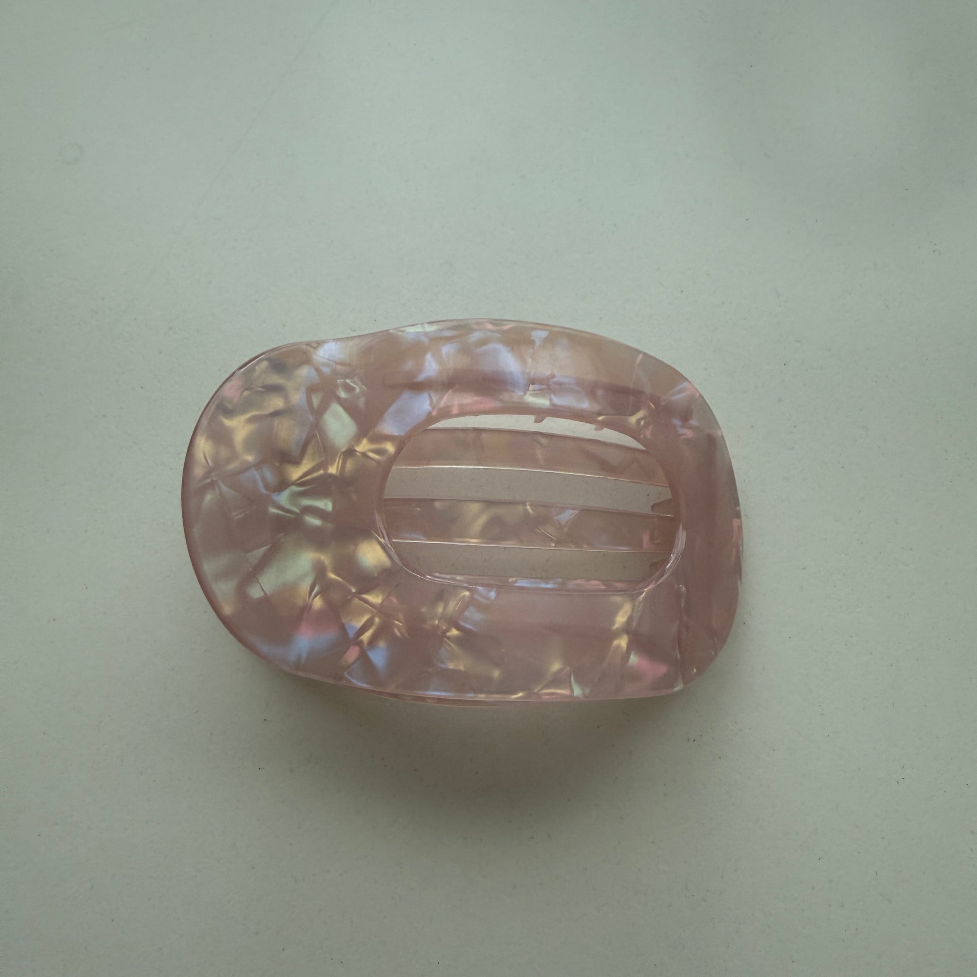 Pink hair clip with marbled pattern on a light green background